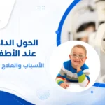 طفل صغير يجلس على كرسي الفحص لدى طبيب عيون أطفال، والطبيب يستخدم منظاراً لفحص عينيه، مع تركيز على العينين لتوضيح فحص الحول الداخلي